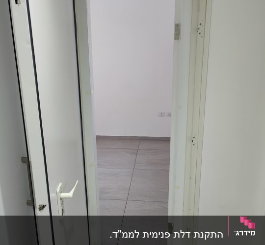 דלת לבנה פתוחה עם ידית לבנה וחלקי צירים